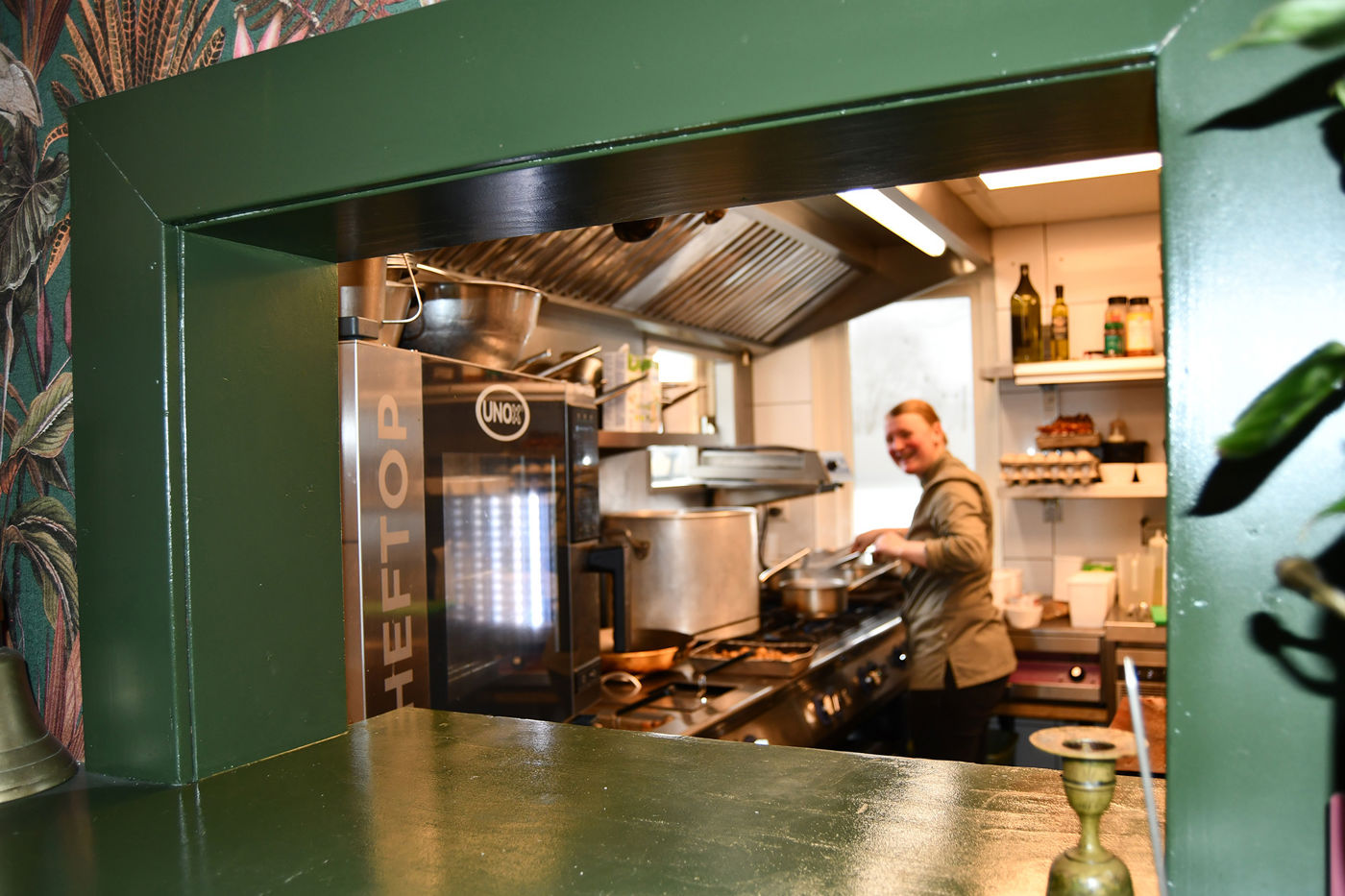 Les Deux Ponts doorkijk naar de keuken waar lachende kok aan het werk is Les Deux Ponts doorkijk naar de keuken waar lachende kok aan het werk is
